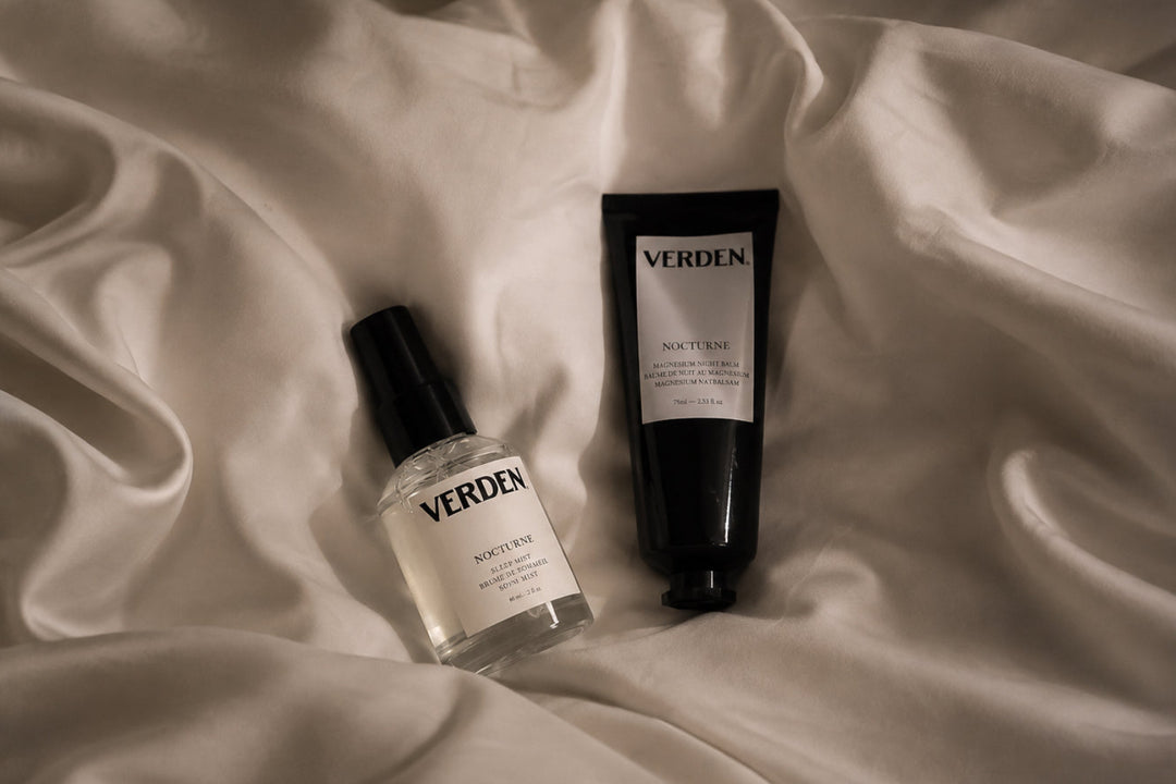 A bottle of VERDEN Nocturne body mist and a black tube of VERDEN Nocturne hand cream arranged on draped white fabric.